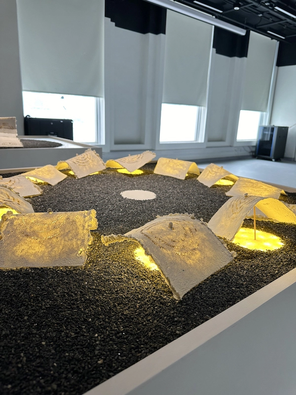 A laser's fine beam, a scribe of light, carves the participants' words into the reborn texture of handmade paper.