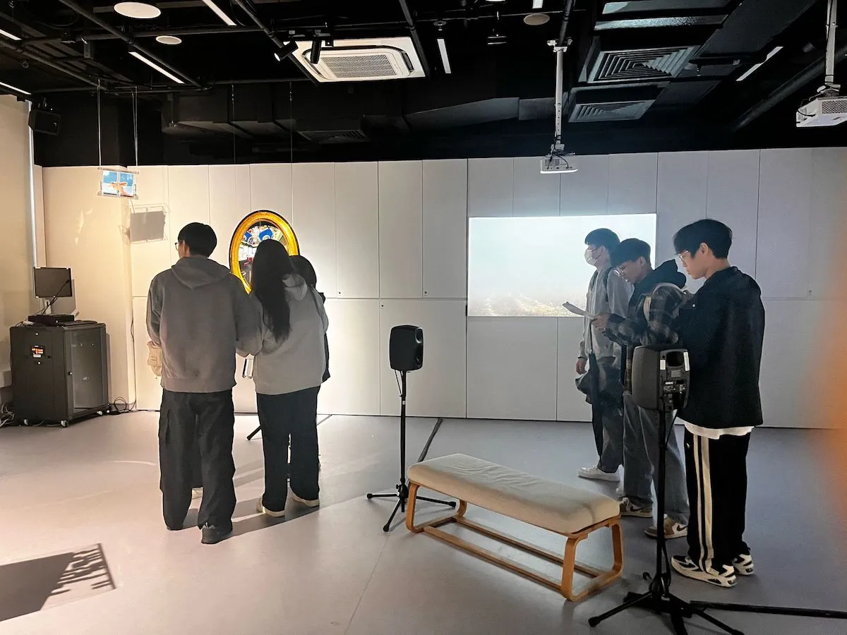 Spectators are drawn to the landscape suspended in mid-air, appearing both as a room untethered and a private booth floating above serene waters, hovering between worlds both familiar and dreamlike.